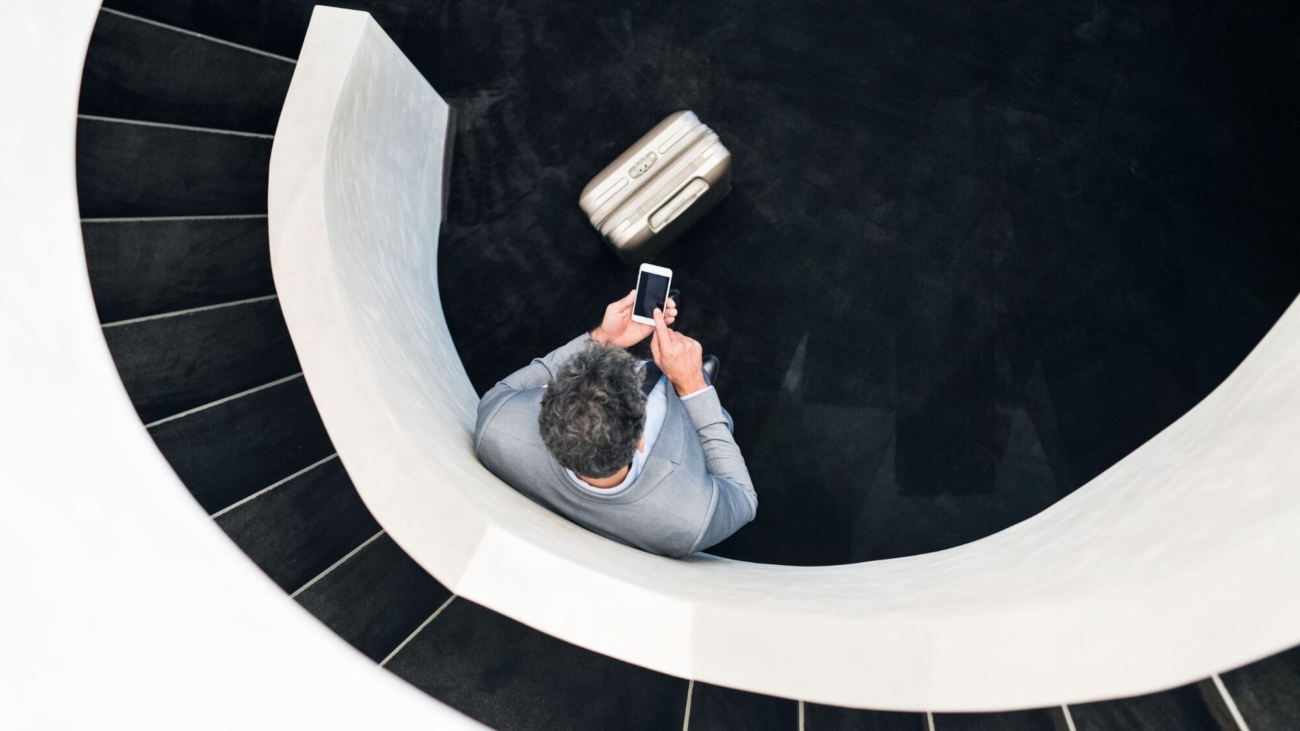 Businessman-with-smartphone-standing-at-staircase.@2x-min